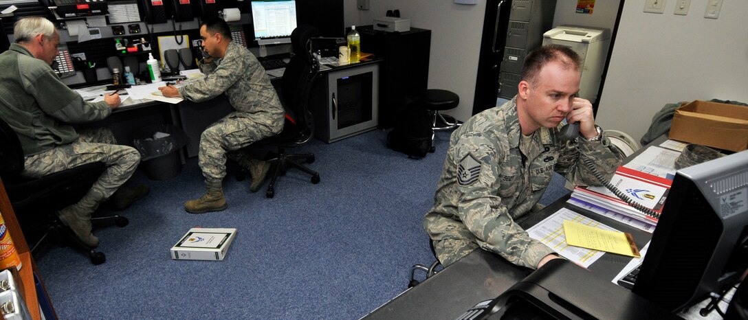 MISAWA AIR BASE, Japan -- Tech. Sgt. John Hamilton, left, and Lt. Col. Tony Jarry, coordinate a telephone recall of base leadership while Master Sgt. William Scott, confirms heavy airlift into Misawa for Operation Tomodachi relief efforts 19 April. All three Airmen are members of the 35th Fighter Wing's Command Post. (U.S. Air Force photo by Tech. Sgt. Phillip Butterfield\Released)