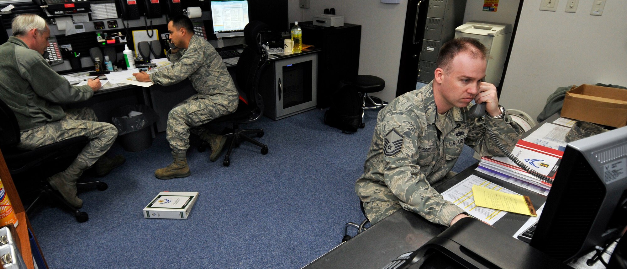 MISAWA AIR BASE, Japan -- Tech. Sgt. John Hamilton, left, and Lt. Col. Tony Jarry, coordinate a telephone recall of base leadership while Master Sgt. William Scott, confirms heavy airlift into Misawa for Operation Tomodachi relief efforts 19 April. All three Airmen are members of the 35th Fighter Wing's Command Post. (U.S. Air Force photo by Tech. Sgt. Phillip Butterfield\Released)