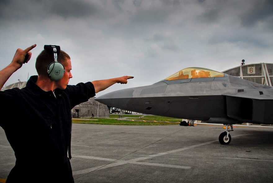 An crew chief from Joint Base Elmendorf-Richardson’s 525th Aircraft Maintenance Unit signals Capt. Brad Roberts, 525th Fighter Squadron F-22 pilot, to prepare to taxi onto Kadena’s flight line, March 31. During their stay with the 18th Wing, the group of F-22 Raptors, their pilots and maintainers from JBER has worked hand-in-hand with Kadena’s Airmen and aircraft from numerous squadrons on the base and also with Marines and their aircraft from Marine Corps bases on-island, to train and build a greater Pacific presence. (U.S. Air Force photo/ Airman 1st Class Maeson L. Elleman)