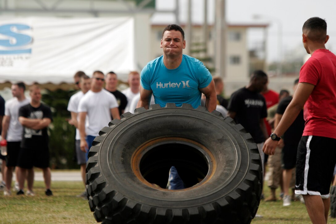 A Marine with Combat Logistics Battalion 31, 31st Marine Expeditionary Unit, competes against other Marines in a tire flipping contest during a field meet, April 22. The field meet included events such as an ammunition can lift, egg toss, tug of war, and many other events that build unit camaraderie.