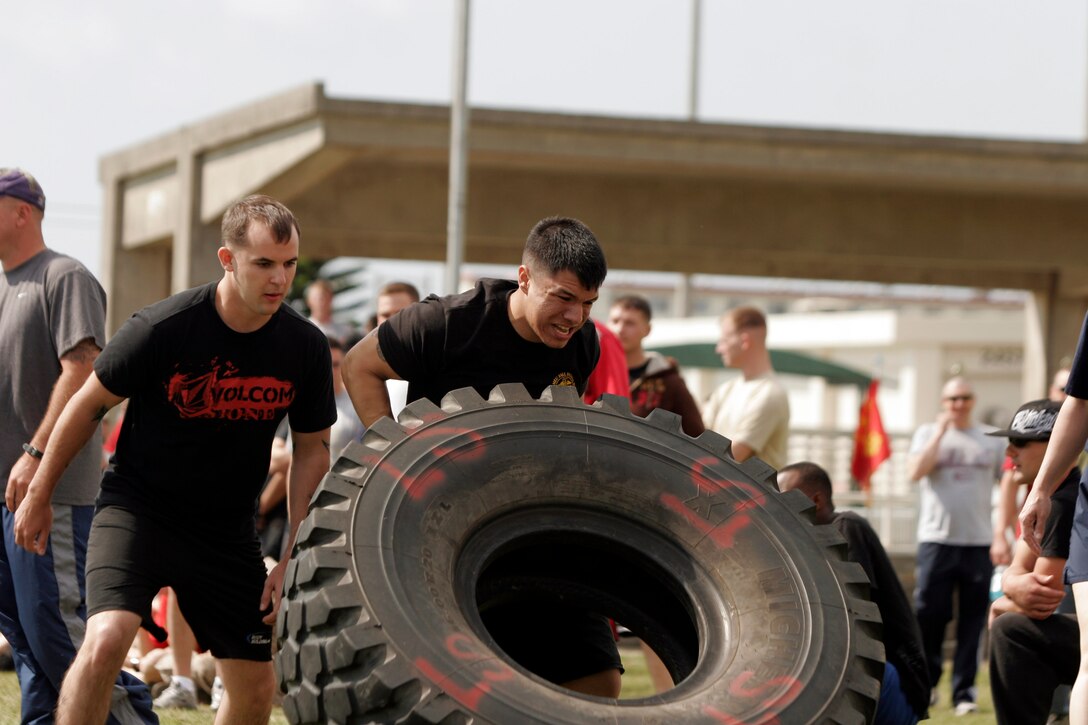 A Marine with Combat Logistics Battalion 31, 31st Marine Expeditionary Unit, competes against other Marines in a tire flipping contest during a field meet, April 22. The field meet included events such as an ammunition can lift, egg toss, tug of war, and many other events that build unit camaraderie. ::r::::n::::r::::n::
