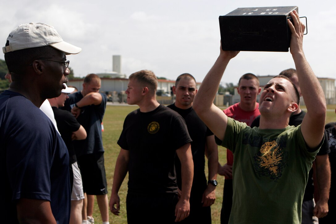 Lance Cpl. Benjamin W. Palmer (right), a combat engineer with Combat Logistics Battalion 31, 31st Marine Expeditionary Unit, competes in an ammunition can lift contest as Sgt. Maj. Anthony P. Goss (left), CLB-31 sergeant major, counts the repetitions, April 22. The ammunition can lift was part of a CLB-31 field meet that included events such as a tire flipping contest, egg toss, tug of war, and many other events that build unit camaraderie.