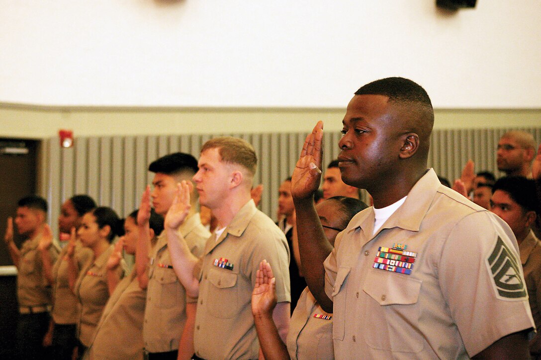 Marines, who are candidates for citizenship, raise their right hands to take the oath of allegiance during a naturalization ceremony at the Camp Foster theater April 22.