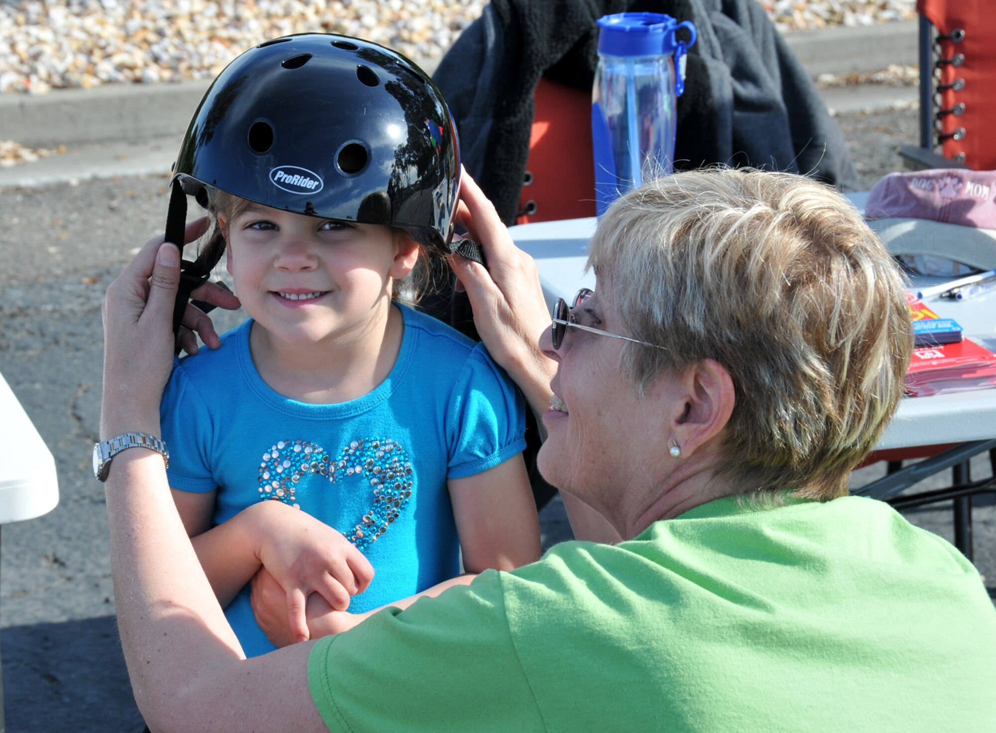 Susan Clabby, 60th Air Mobility Wing ground safety specialist, fits Annabelle Sloan with a bike helmet at the Health, Safety and Wellness Fir held here on April 16. Annabelle’s father, Tech Sgt. Raymond Sloan, is assigned to the 860th Aircraft Maintenance Squadron.