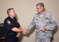 Col. Timothy Tarchick, commander 94th Airlift Wing, thanks Smyrna police officer, Lt. Joe Bennett and presents him with a commander's coin for his diligence and "Eagle Eyes", Apr 21.  Last month while on patrol near the Walmart on Cobb Parkway, Officer Bennett observed a man taking photographs in the direction of the runway and base facilities at Dobbins.  Upon further investigation officer Bennett found the man was a foreign national and detained him.   (U.S. Air Force photo/ Brad Fallin)