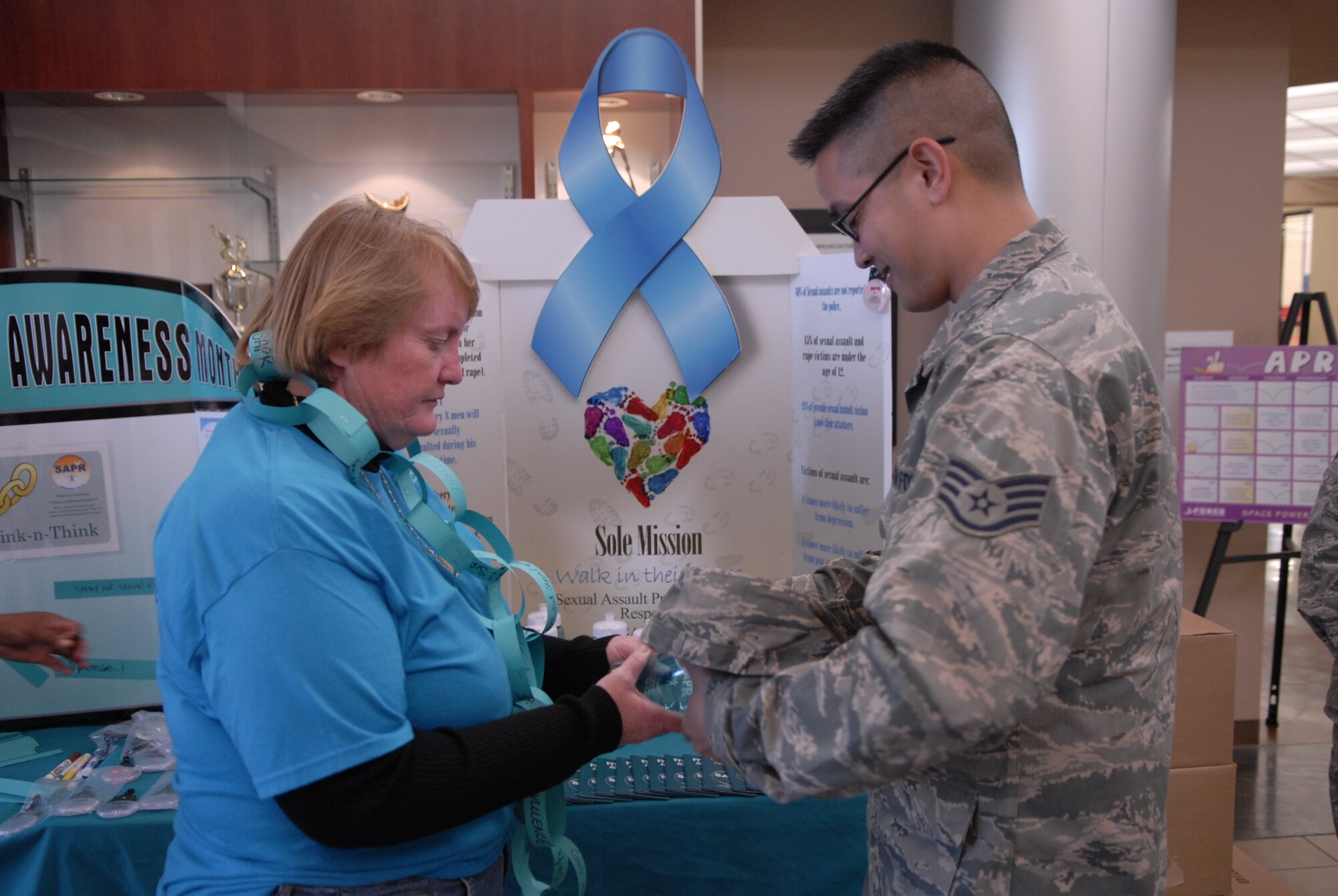 VANDENBERG AIR FORCE BASE, Calif. -- Sharing the message, Donna Rathbun, the 30th Space Wing sexual assault response coordinator, gives Staff Sgt. George Solis, a 30th Space Wing combat correspondent, educational material on sexual assault awareness at the base fitness center Thursday, April 14, 2011.  Members from the Sexual Assault Prevention and Response office promote sexual assault awareness every day to keep the base community safe.  (U.S. Air Force photo/Staff Sgt. Andrew Satran) 

 