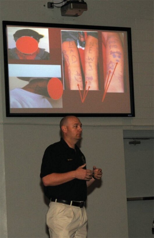 Sgt. L.W. Spencer, Newport News Police Department Gang Enforcement Unit supervisor, discusses various types of gang tattoos or markings in a presentation during the Joint-Base Langley-Eustis Gang Awareness Briefing April 11 at Jacobs Theater. (U.S. Air Force Photo/Tetaun Moffett)