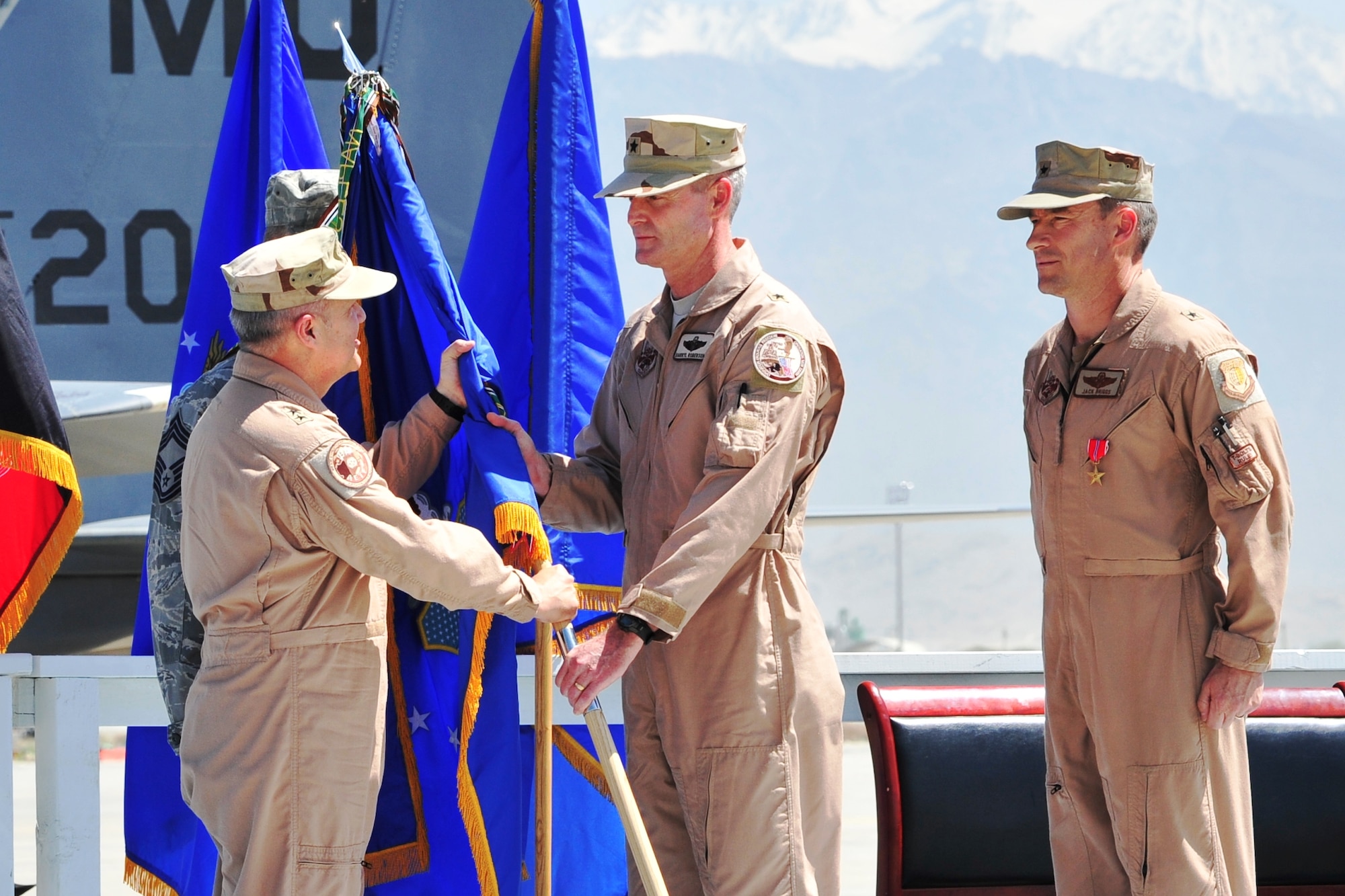 Maj. Gen. Charles W. Lyon (left), 9th Air and Space Expeditionary Task Force-Afghanistan commander, passes the 455th Air Expeditionary Wing guidon to Brig. Gen. Darryl Roberson, new 455th AEW commander, as Brig. Gen. Jack L. Briggs II, former 455th AEW commander, stands at attention.  The ceremony at Bagram Airfield, April 22, 2011, marked the change of command for Afghanistan’s largest air expeditionary wing. (U.S. Air Force photo by Capt. Erick Saks)