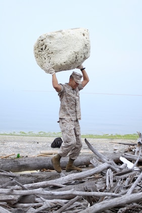 Lance Cpl. Jose Landaverdediaz, Combat Logistics Company 36 automotive organizational mechanic, carries a large piece of plastic foam over a pile of wood during a seawall clean-up near Penny Lake during an Earth Day celebration here April 22.  More than 80 Marines, sailors and volunteers showed up to participate in the cleanup.