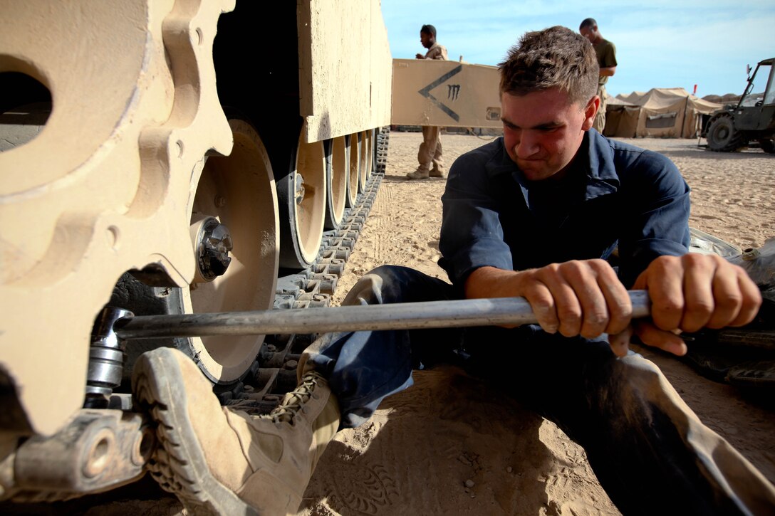 Lance Cpl. Brandon Chisholm pulls hard on a wrench to remove a track pad. The Abbot, Maine, native is a tank operator with 1st Tank Battalion, 1st Marine Regiment, 2nd Marine Division (Forward). Chisholm and his team of Marines work tirelessly to maintain their M-1A1 “Abrams” Main Battle Tanks.::r::::n::::r::::n::::r::::n::