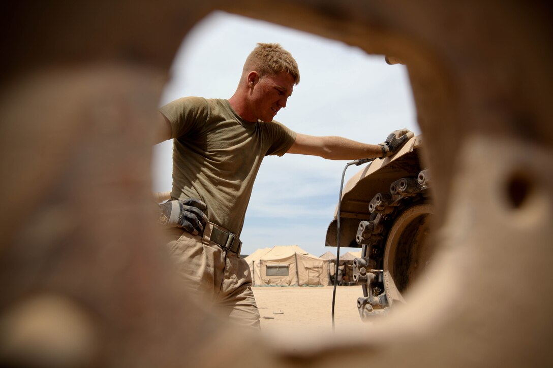 A small, two-inch hole on a side panel door of an M-1A1 “Abrams” Main Battle Tank reveals Gonzales, Texas, native Lance Cpl. Kevin Kuntschik pausing for short break. The tank gunner with 1st Tank Battalion, 1st Marine Regiment, 2nd Marine Division (Forward), mans the main gun on the tank and works tirelessly to maintain the M-1A1 “Abrams” Main Battle Tanks.::r::::n::::r::::n::::r::::n::