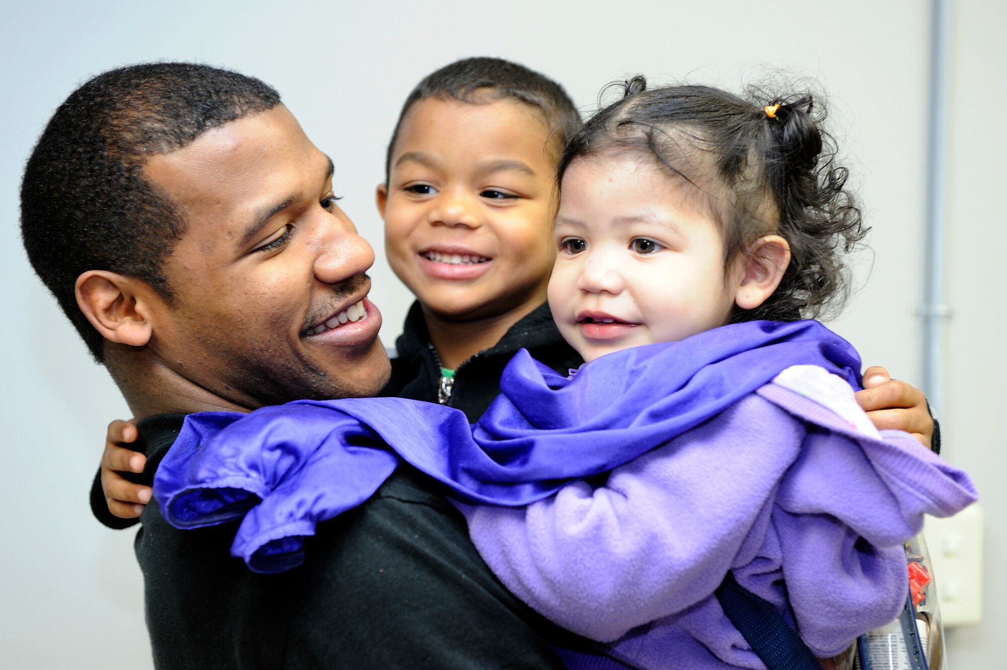 MISAWA AIR BASE, Japan -- Senior Airman Kai Hall, 35th Communications Squadron, gets big hugs from his son Izaiah, and daughter Aniyah, 22 April. Airman Hall's wife Christina and children returned to Misawa on the first patriot express flight along with more than 150 other passengers. The families were in the United States as part of the Department of State-authorized voluntary departure program.  (U.S. Air Force photo by Staff Sgt. Marie Brown\Released)