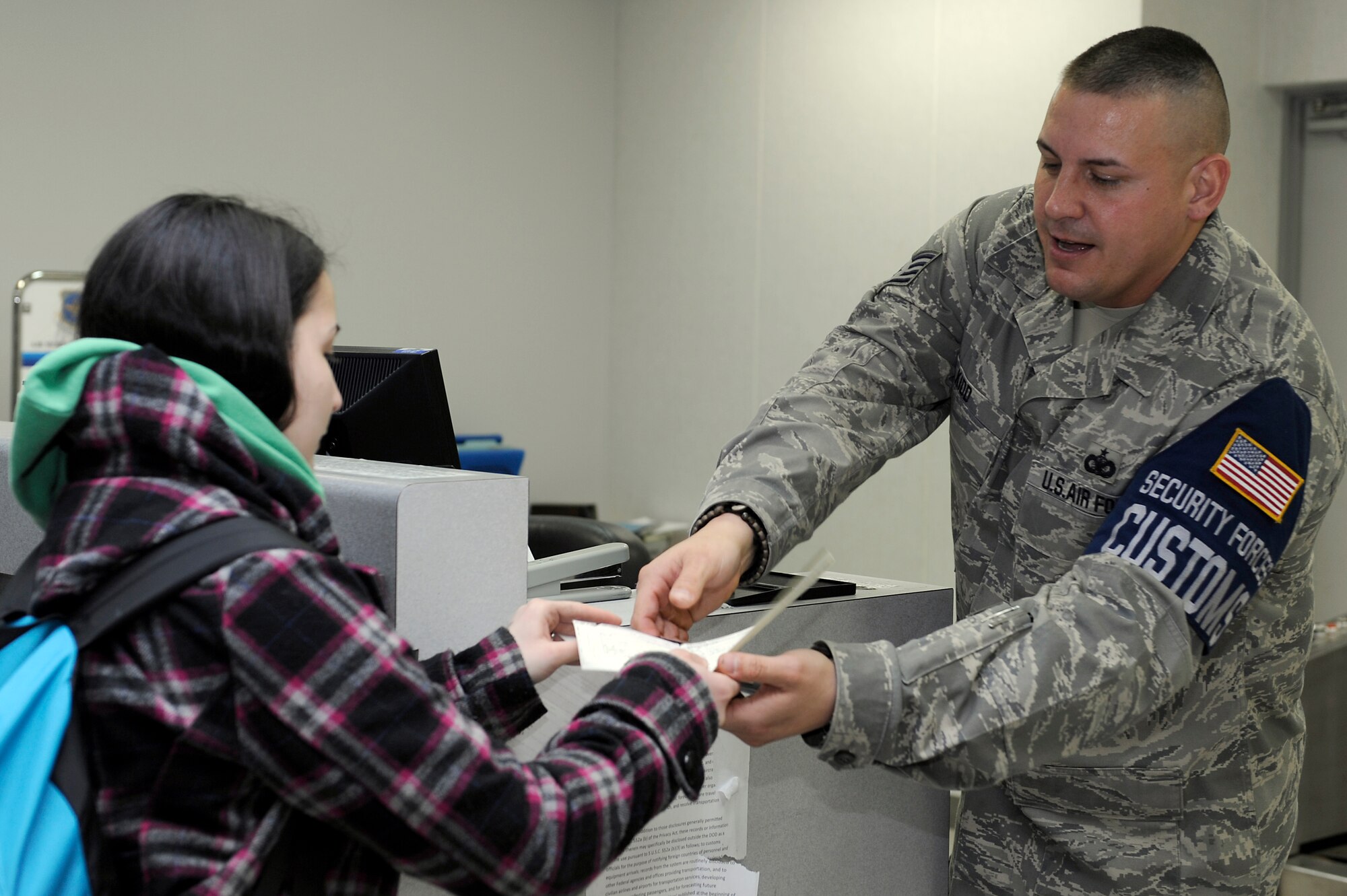 MISAWA AIR BASE, Japan -- Staff Sgt. Jason Kidd, 35th Security Forces customs officer, ensures Nicole Way, spouse of Senior Airman Christopher Way, 35th Communications Squadron, clears customs 22 April. Military family members, Defense Department civilians and contractors assigned to mainland Japan were eligible to depart for a period not to exceed 30 days. (U.S. Air Force photo by Staff Sgt. Marie Brown\Released)