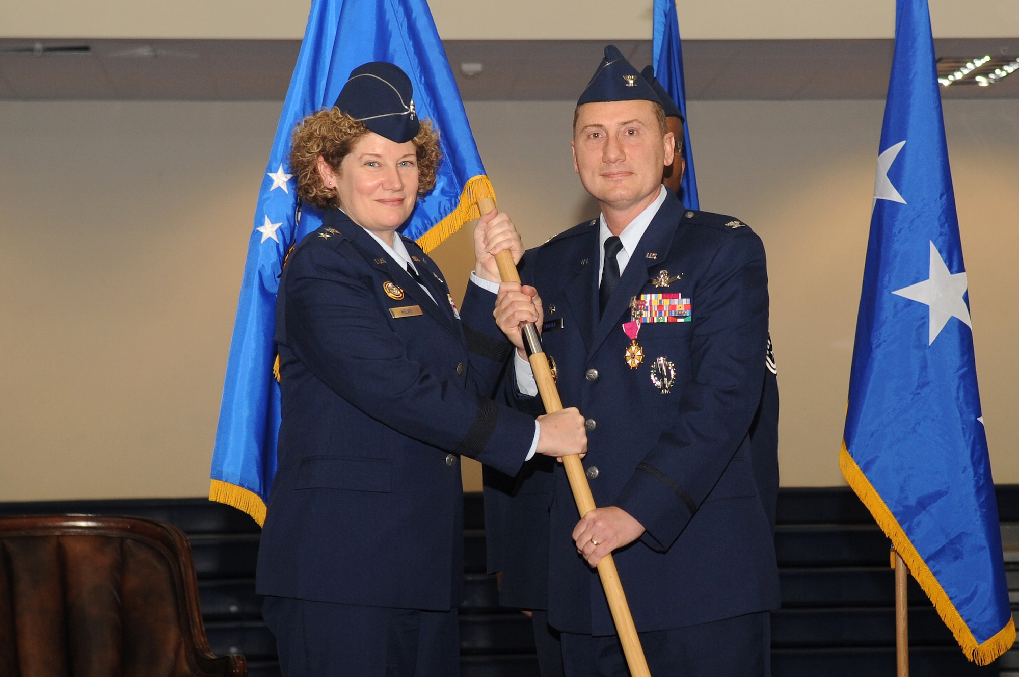 BUCKLEY AIR FORCE BASE, Colo.-- 460th Space Wing Commander, Col. Clint Crosier, passes the Air Force flag to the 14th Air Force Commander, Lt. Gen. Susan Helms, during his reliquishment of command ceremony at the Buckley Fitness Center April 25, 2011. Col. Trent Pickering, will take his place as base commander. (U.S. Air Force photo by Airman Manisha Vasquez)