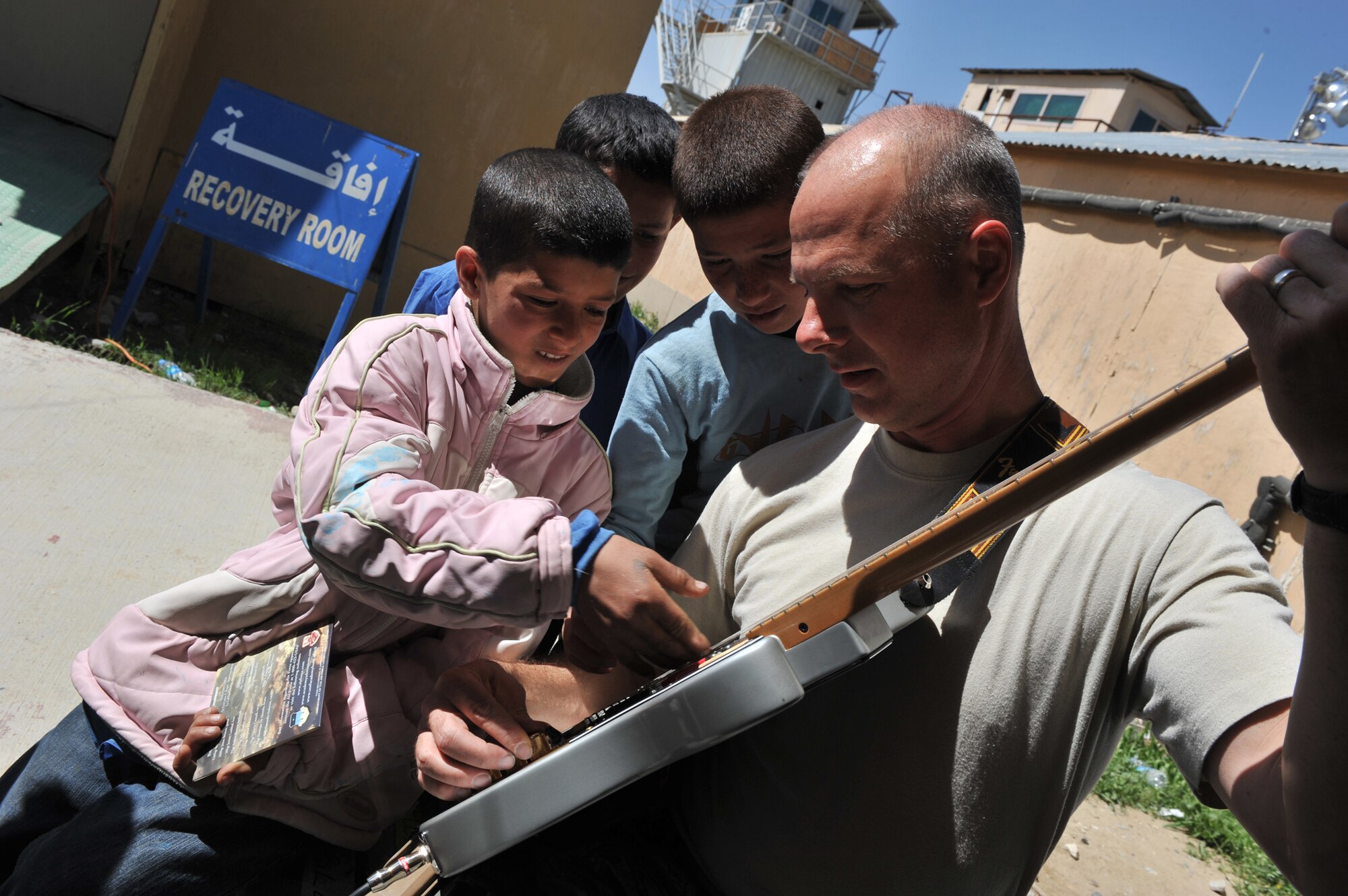 Tech. Sgt. Stephen Brannen, a U.S. Air Force Central Expeditionary Band guitarist and vocalist, allows Afghan children to play his guitar, April 20, 2011, at the Egyptian Field Hospital at Bagram Airfield, Afghanistan. (U.S. Air Force photo/Senior Airman Sheila deVera)