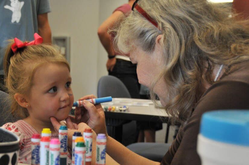 Two-year-old Hayden Robinson, daughter of Tech. Sgt. Sean Robinson from the 437th Maintenance Squadron, gets her face painted by volunteer Kathy Perry, April 23, during a children?s deployment line at Joint Base Charleston - Air Base. The deployment line code named ?Treasures of Monaco,? included a walk-through of the 628th Logistics Readiness Squadron, a C-17 tour and a visit from McGruff, the crime fighting dog. (U.S. Air Force photo /Airman 1st Class Jared Trimarchi)
