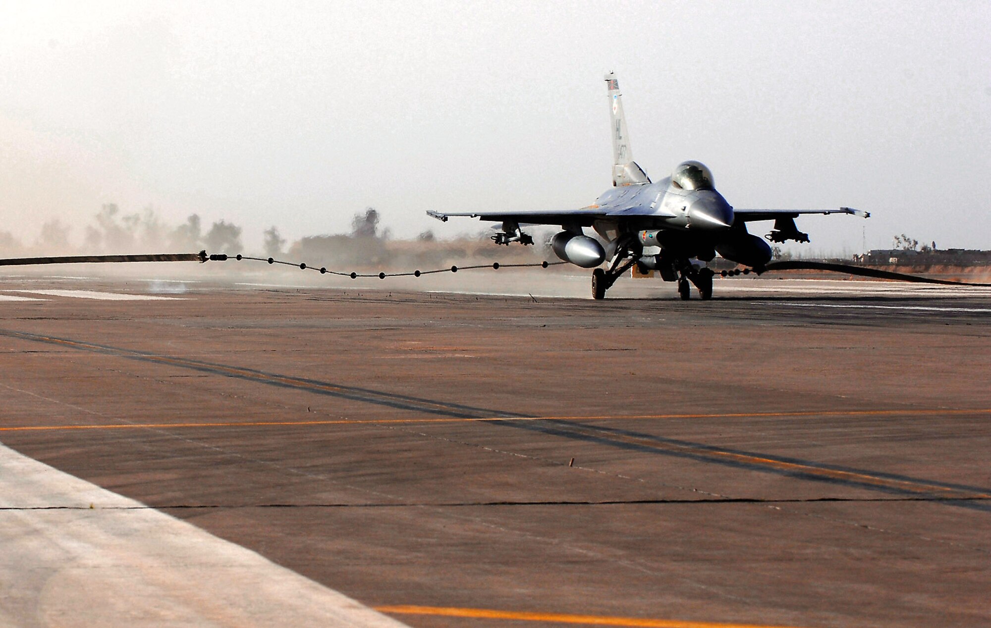 An F-16 Fighting Falcon catches the cable during a certification test of an aircraft arresting system at Balad Air Base, Iraq. The system went through a certification test with an actual F-16 Fighting Falcon to ensure its operability following installation by the 332nd Expeditionary Civil Engineer Squadron. (U.S. Air Force photo/Senior Airman Julianne Showalter)