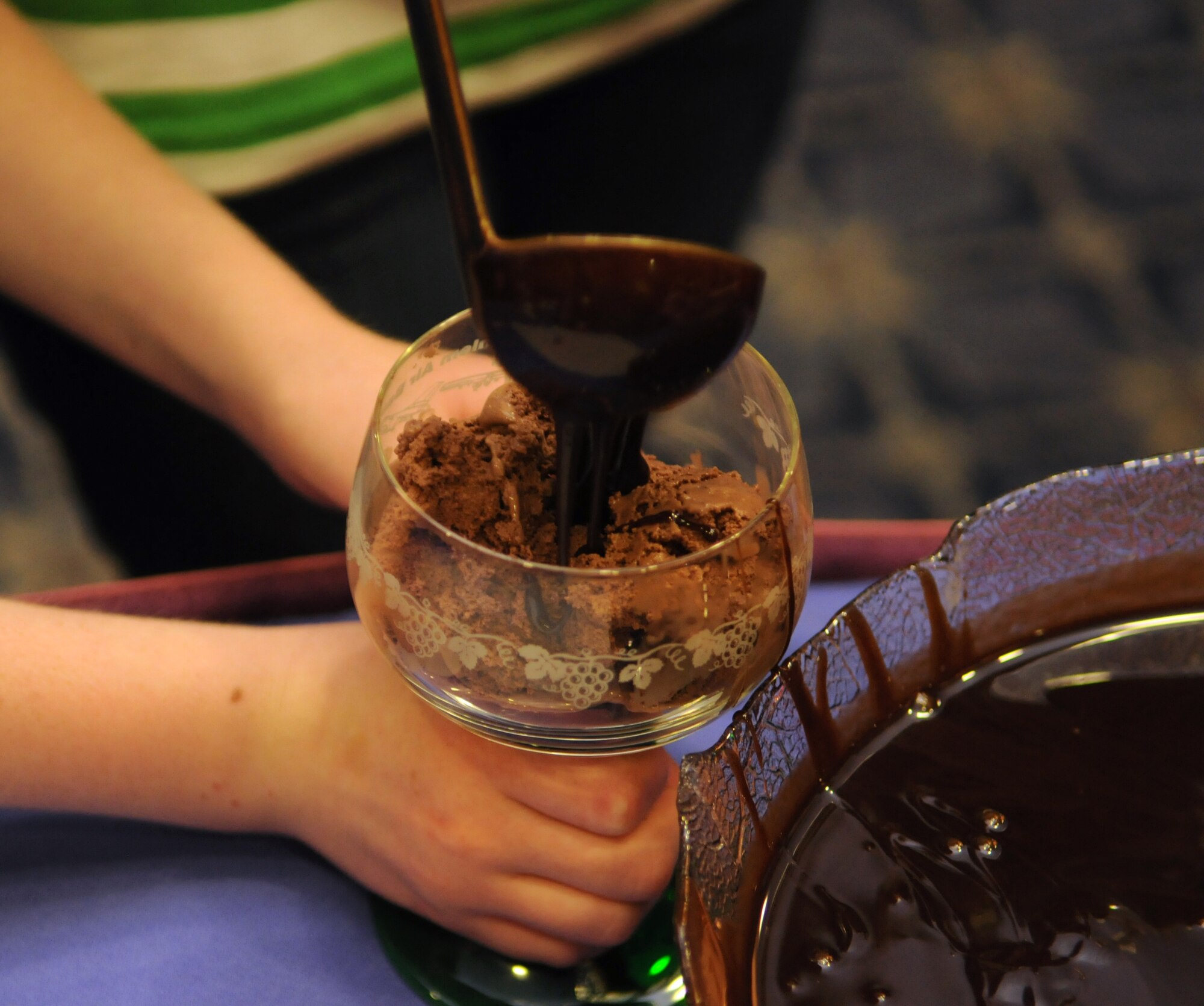 SPANGDAHLEM AIR BASE, Germany – A child pours chocolate syrup on ice cream during a 52nd Fighter Wing volunteer recognition ceremony at Club Eifel April 21. The ceremony was combined with an ice-cream social to thank wing volunteers for their efforts throughout the year. (U.S. Air Force photo/Staff Sgt. Benjamin Wilson)