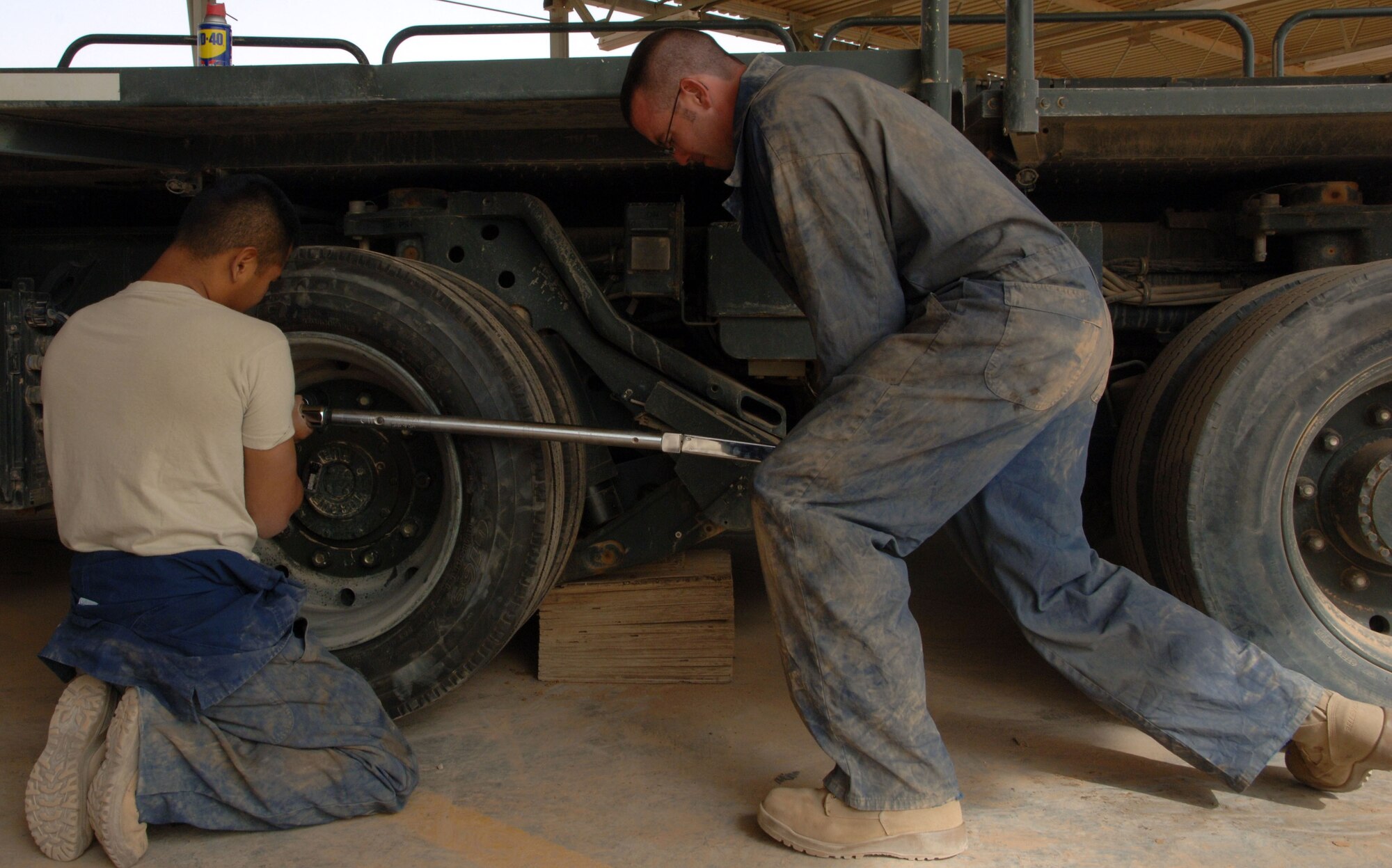 Senior Airman Greg Weiss (left), a Lady Lake, Fla., native, and Staff Sgt. Todd Hickman, a Auburndale, Fla., native, tighten the lug nuts on a 60K Cargo Loader after replacing a tire April 18, 2011, at Al Asad Air Base, Iraq. The mechanics are assigned to the 532nd Expeditionary Operation Support Squadron Vehicle Maintenance Element, which is responsible for maintaining a 68 vehicle fleet worth more than $18 million. (U.S. Air Force photo by Staff Sgt. R. Michael Longoria/Released)