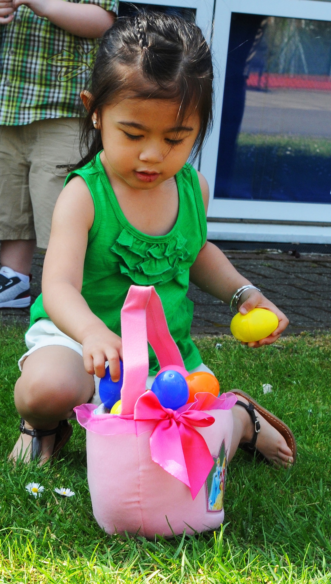 RAF MILDENHALL, England -- Xiomara, 2, daughter of Staff Sgt. Joseph James, 100th Aircraft Maintenance Squadron, gathers eggs at the RAF Mildenhall Youth Center's Easter Egg Hunt April 24. Hundreds of children participated in the family-friendly event that also had bouncy castles and a visit from the Easter Bunny. (U.S. Air Force photo/Staff Sgt. Thomas Trower) 