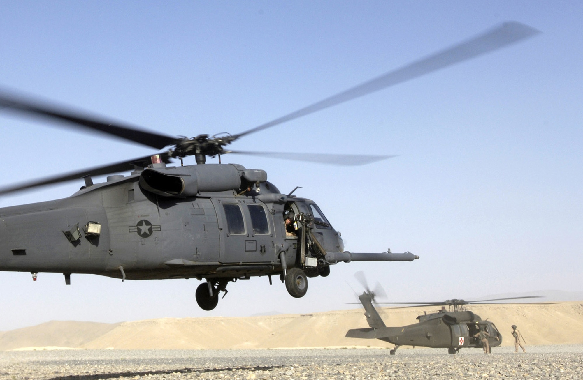An HH-60G Pave Hawk helicopter lands as an Army UH-60 Black Hawk prepares to pick up a medivac patient.  The HH-60G is a twin-engine medium-lift helicopter used in combat search and rescue missions. (U.S. Air Force photo)