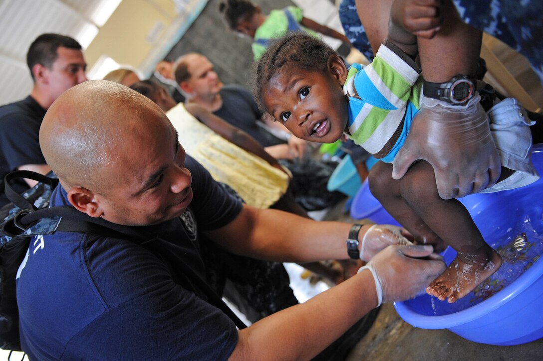 U.S. Navy Petty Officer 2nd Class Jasmin Copeland washes a girl's feet before 
measuring them for correct shoe size during a Continuing Promise community event in Kingston, Jamaica, April 21, 2011.