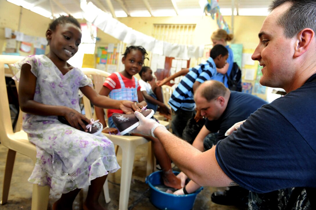 A U.S. Navy sailor hands a little girl a new pair of shoes during a Continuing Promise community event in Kingston, Jamaica, April 21, 2011.