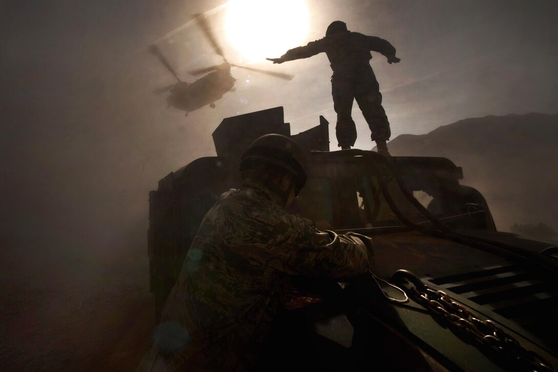 U.S. Army Staff Sgt. Hector Hoyas waves off a Nevada Army National Guard CH-47 Chinook helicopter while Air Force airmen secure the mirrors of a Humvee during sling-load training on Nellis Air Force Base, Nev., April 15, 2011. Hoyas is an aerial delivery field service department instructor assigned to Fort Lee, Va.