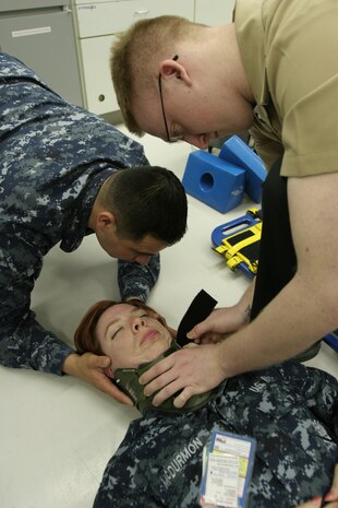 Seaman Apprentice Edgar Moreno, a Daniel M. Casey Medical and Dental Clinic corpsmen and Emergency Medical Technician-Basic course participant, and Seaman Apprentice Perry M. Lynch, a BHC corpsmen and EMT-B course participant, secure Petty Officer 2nd Class Jessica M. McDurmon in a neck brace in a practical application exercise of spinal immobilization during the EMT-B course at the BHC here April 26.