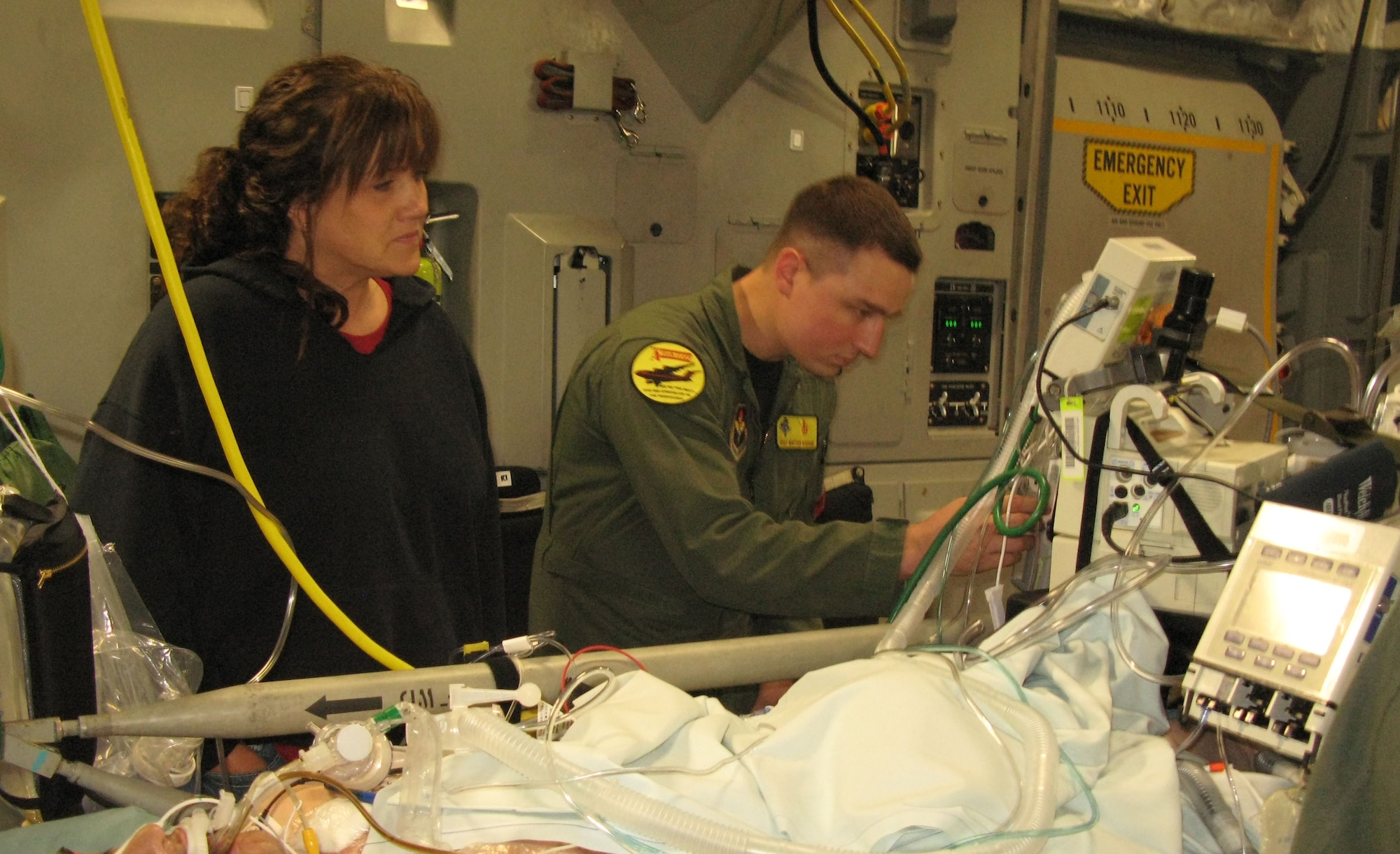 Kelli Pedersen looks on as Staff Sgt. Matthew Worsham, a respiratory technician with the critical care air transport team, prepares her son, Army Spc. Dustin Morrison, for an aeromedical evacuation flight from Ramstein Air Base, Germany, April 26, 2011, for follow-on care at Walter Reed Army Medical Center in Washington, D.C. (Defense Department photo/Donna Miles )