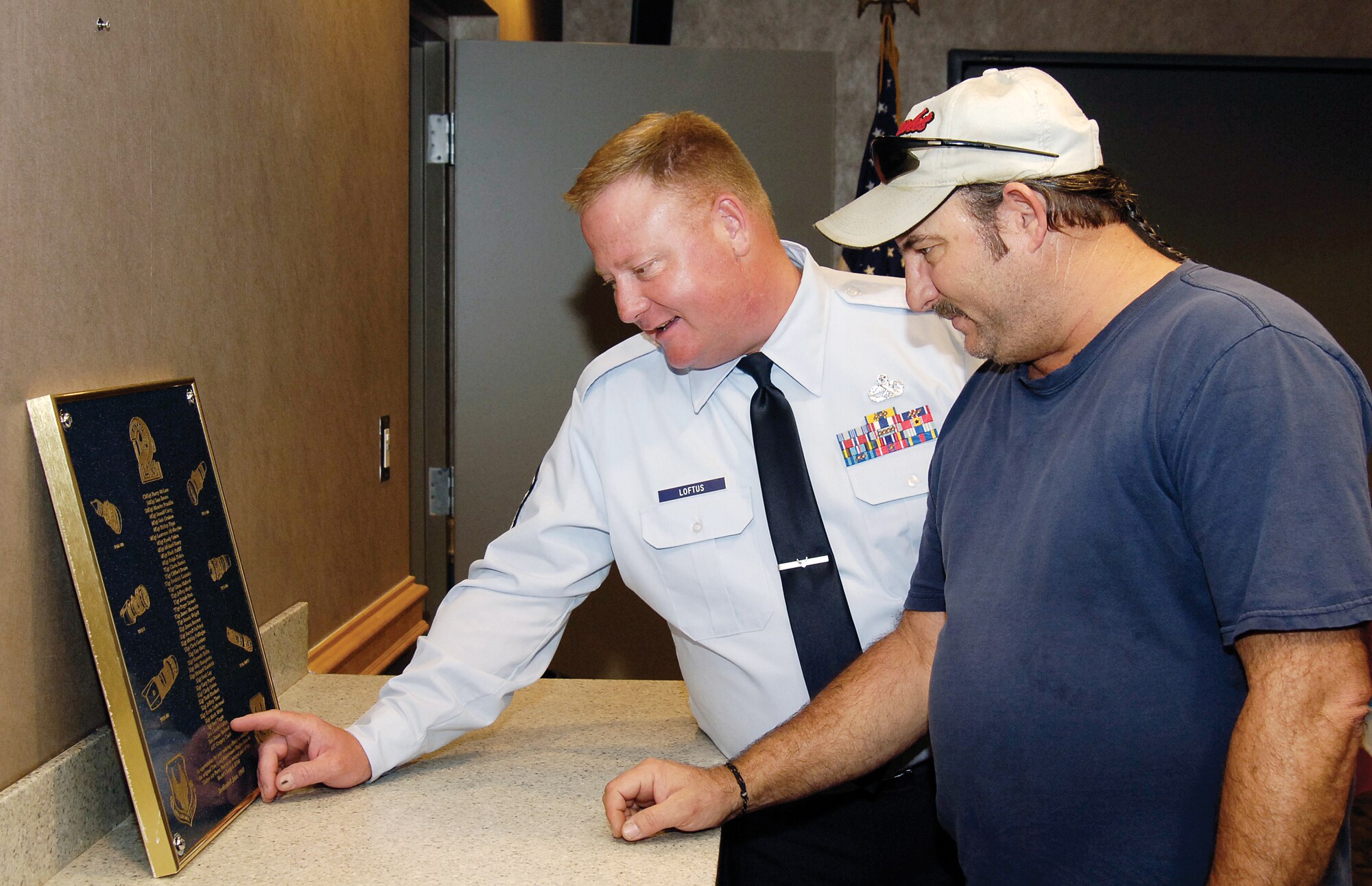 Master Sgt. Chuck Loftus and Mickey Fullingim find familiar names on a 1997 plaque that hailed a new Engine Two-Level Maintenance system that honed engine repair processes and saved the Air Force millions.  Sergeant Loftus was a senior airman and Mr. Fullingim a staff sergeant when the plaque first was unveiled. Years of depot floor changes hid the plaque behind a free-standing office wall until Steven Lewis, a Propulsion Maintenance Division F108 equipment specialist saw it and set a rededication in motion. Sergeant Loftus is now stationed at Travis Air Force Base, Calif., and Mr. Fullingim is a B-52 sheet metal work leader. (Air Force photo by Margo Wright)
