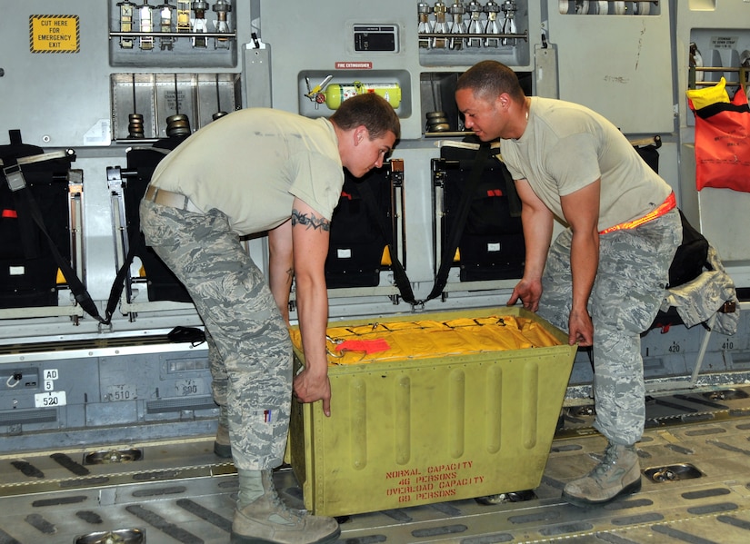 Airman 1st Class Eric Duncan (left) and Senior Airman David Torres lift a 46-person life raft that they removed from a C-17 April 25, on Joint Base Charleston - Air Base. Every three years the life rafts on the C-17 must be replaced. The life rafts are used in case of an emergency water landing and are made to last for many days. Airman Duncan and Airman Torres are crew chiefs from the 437th Aircraft Maintenance Squadron.  (U.S. Air Force photo by /Airman 1st Class Jared Trimarchi)

