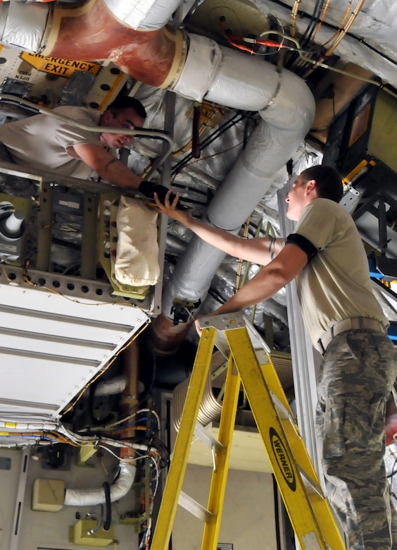 Staff Sgt. Jessy Martin (left) hands a wrench to Airman 1st Class Eric Duncan, to remove a 46-person life raft from a C-17  April 25, on Joint Base Charleston - Air Base. Sergeant Martin and Airman Duncan are crew chiefs from the 437th Aircraft Maintenance Squadron. (U.S. Air Force photo by /Airman 1st Class Jared Trimarchi)
