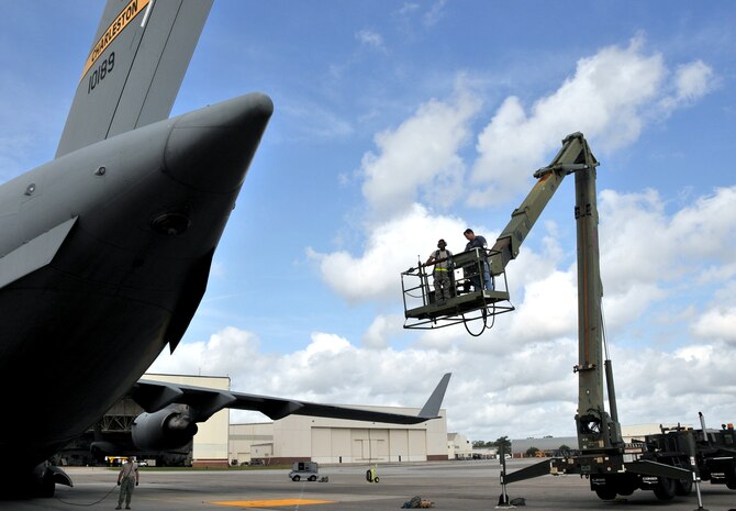 William Rigdon (right) and Senior Airman Charles Barnes, hydraulic technicians from the 437th Aircraft Maintenance Squadron, ride a high reach lift, or Condor, to the tail of a C-17 April 25, on Joint Base Charleston - Air Base. The technicians were thoroughly inspecting the Integrated Flight Control module. Airman Barnes is part of the 437 AMXS team Gold and Mr. Rigdon is part of team Blue. (U.S. Air Force photo by /Airman 1st Class Jared Trimarchi)