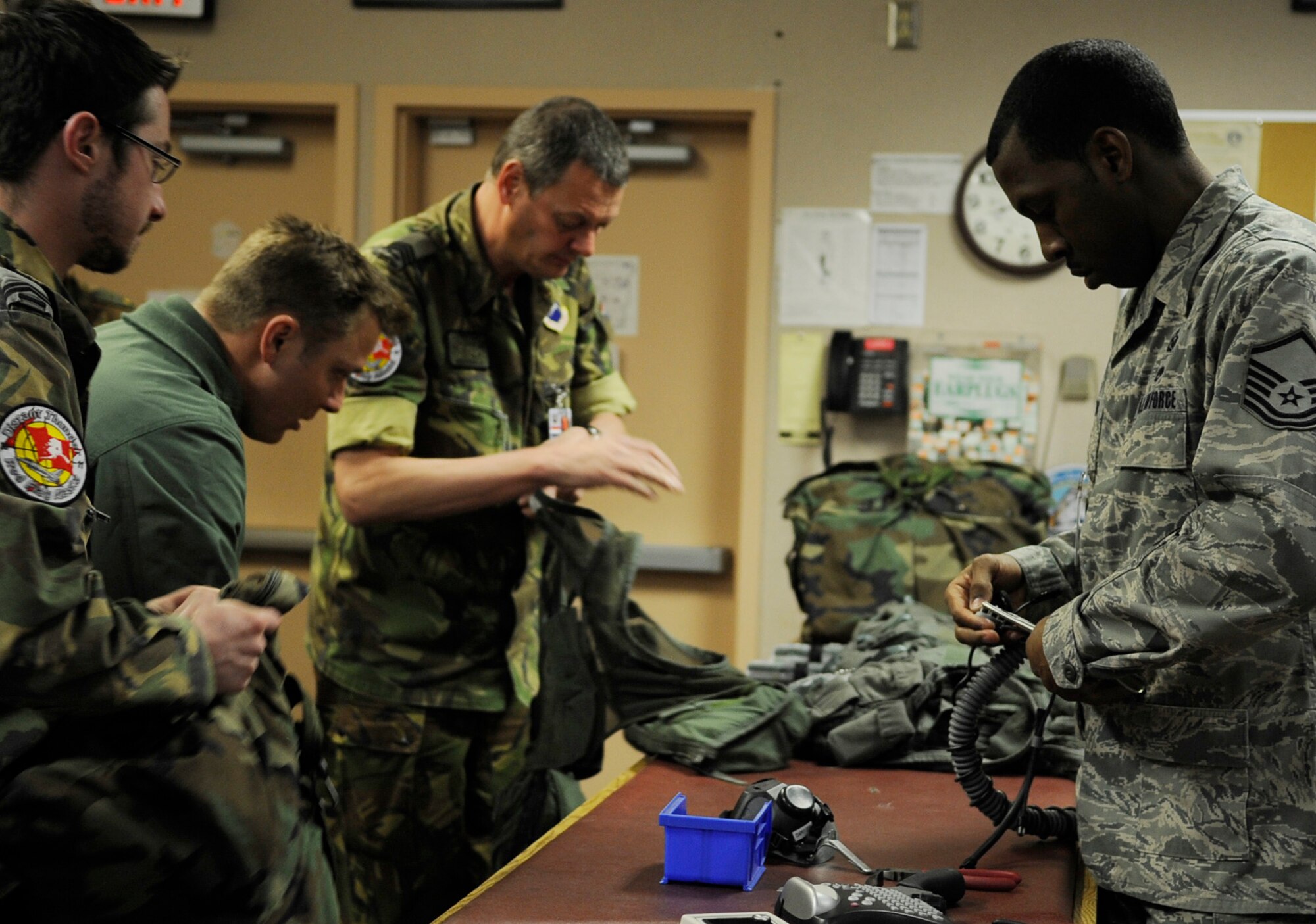 Pilots don aircrew flight equipment while Master Sgt. David Edwards performs final equipment checks in support of RED FLAG-Alaska April 20, 2011, Eielson Air Force Base, Alaska. The Joint Pacific Alaska Range Complex provides the RF-A training mission with over 67,000 square miles of air space, more than 30 threat simulators, one conventional bombing range, and two tactical bombing ranges containing more than 400 different types of targets. The pilots are assigned to the Royal Netherlands air force. Sergeant Edwards, non-commissioned officer in charge of life support, is assigned to Kunsan Air Base, Republic of Korea. (U.S. Air Force photo/Airman 1st Class Laura Goodgame) 