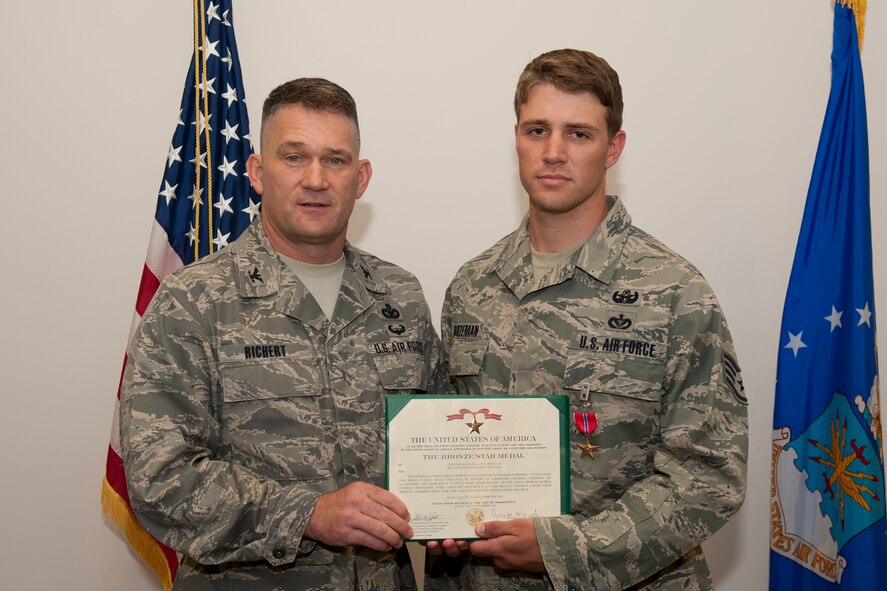Staff Sgt. Dallas Bozeman, 23rd Civil Engineer Squadron explosive ordnance disposal craftsman, receives a Bronze Star Medal certificate from Col. Randall Richert, 820th Base Defense Group commander, April 22 at Moody Air Force Base, Ga. The medal was the first of its kind that Colonel Richert has presented. (U.S. Air Force photo/Staff Sgt. Jamal D. Sutter)(RELEASED)