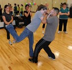 LAUGHLIN AIR FORCE BASE, Texas – Tech. Sgt. Diana Vela and Staff Sgt. Bryan Garcia, both of the 47th Security Forces Squadron, demonstrate self defense techniques to a class at Laughlin’s Losano Fitness Center April 21. The class is in recognition of sexual assault awareness month and takes place at the end of the Zumba classes at the gym. (U.S. Air Force photo by Airman 1st Class Blake Mize)