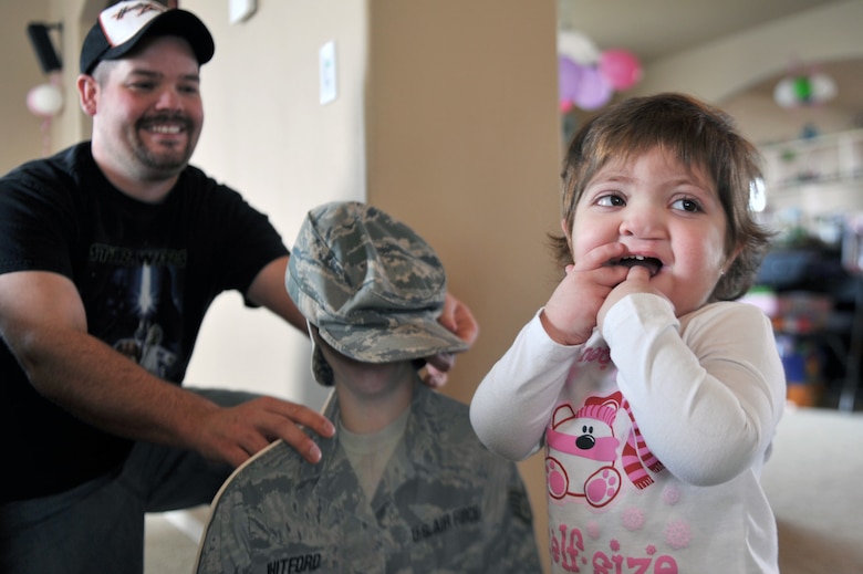 Braelyn Whitford smiles after putting a ABU cap on a cut-out of her mothers head with her father, Matt, at their home in Spokane, Wash., on Apr. 5, 2011. Braelyn is diagnosed with Kabuki Syndrome. Braelyn and her family are assisted through the Exceptional Family Member Program which connects active duty family members who have special needs with many helping agencies both on- and off- base. (U.S. Air Force photo/Staff Sgt. Desiree N. Palacios)
