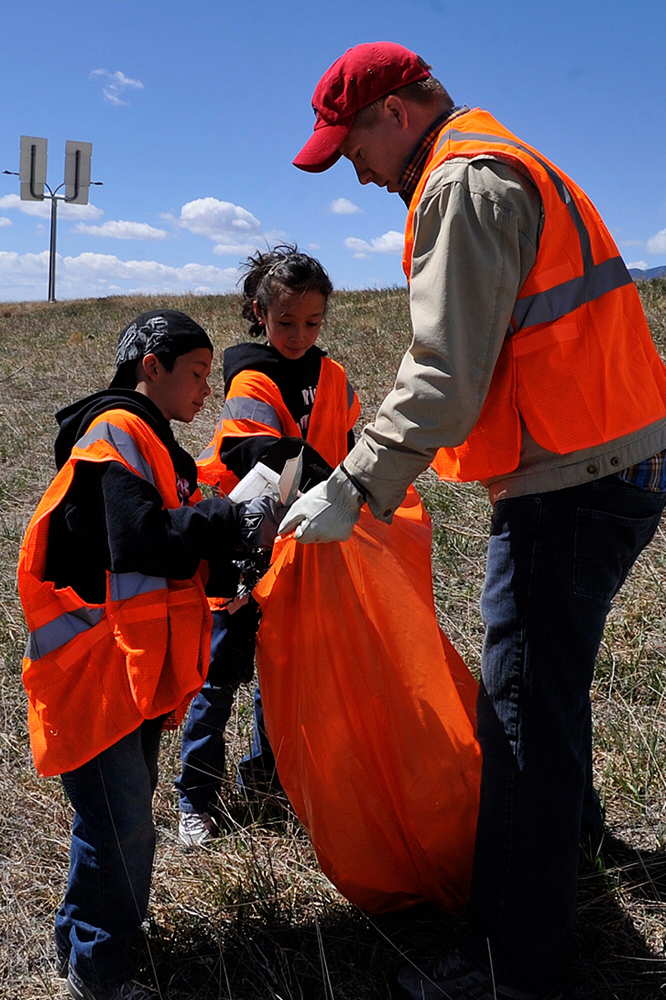 PETERSON AIR FORCE BASE, Colo. -- Twins Jayden and Olivia Linta help Mark Dobbs, 21st Civil Engineer Squadron, fill a bag with trash and debris from northbound Powers Boulevard during the 21st Space Wing’s trash pickup event April 22, 2011 to recognize Earth Day. Earth Day was first celebrated on April 22, 1970 and that year an estimated 22 million people participated in events throughout the United States. This year, an estimated 1 billion people in more than 180 countries were expected to celebrate Earth Day. The 21st Space Wing celebrated Earth Day with a number of events including a tree-planting ceremony, energy awareness booths at the BX, and a youth poster contest. (U.S. Air Force photo/Rob Bussard)