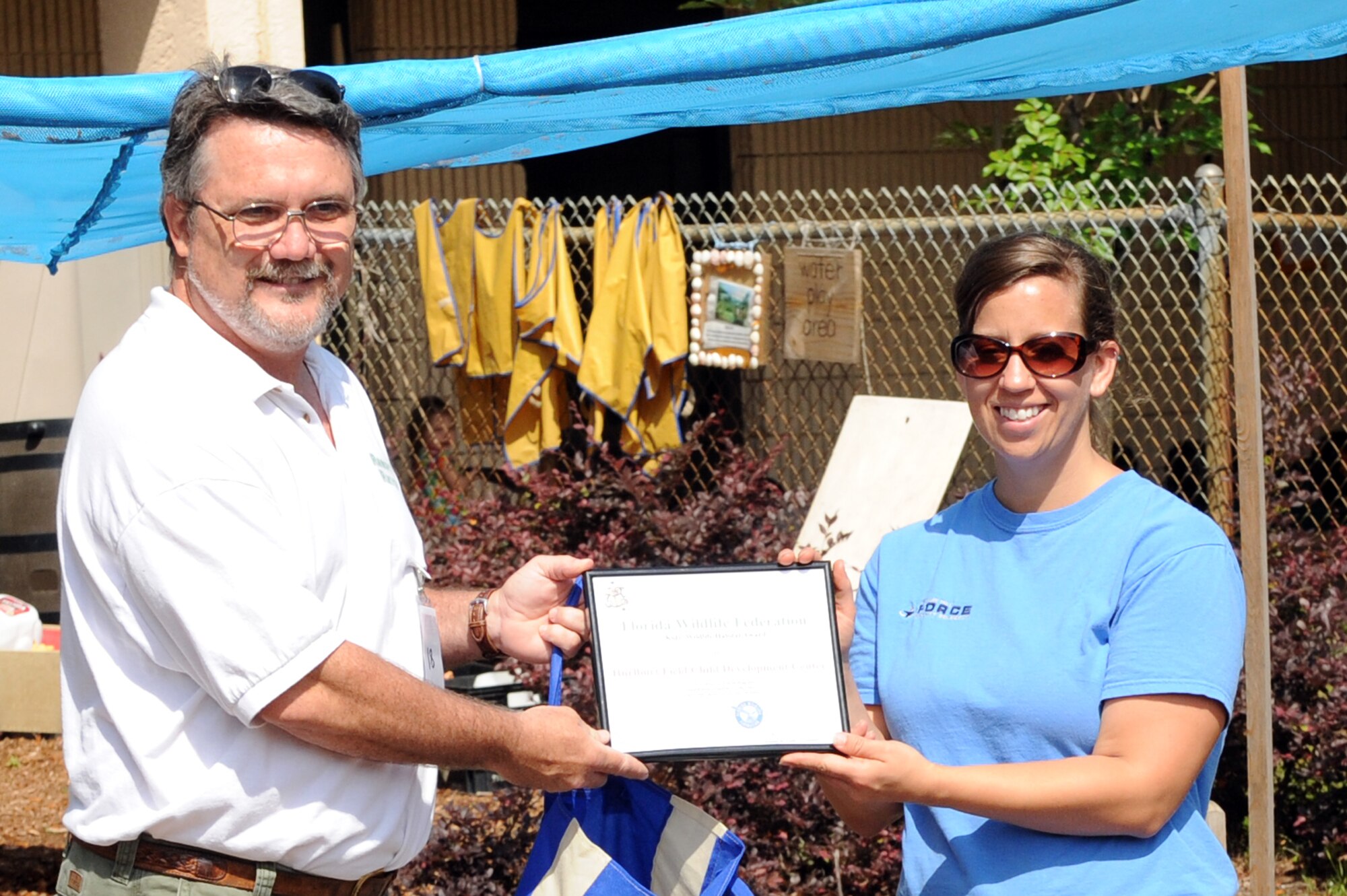 Glenn Griffith, Florida Wildlife Federation board member, left, presents a plaque to Meggie O’Brien, outdoor program coordinator, during a presentation at the child development center at Hurlburt Field, Fla., April 22, 2011.  The CDC’s nature habitat was named the winner of the FWF’s second annual Kid’s Habitat Contest for excellence in maintaining a schoolyard environment for the study and preservation of Florida’s wildlife. (U.S. Air Force photo by Airman 1st Class Caitlin O’Neil-McKeown / RELEASED)