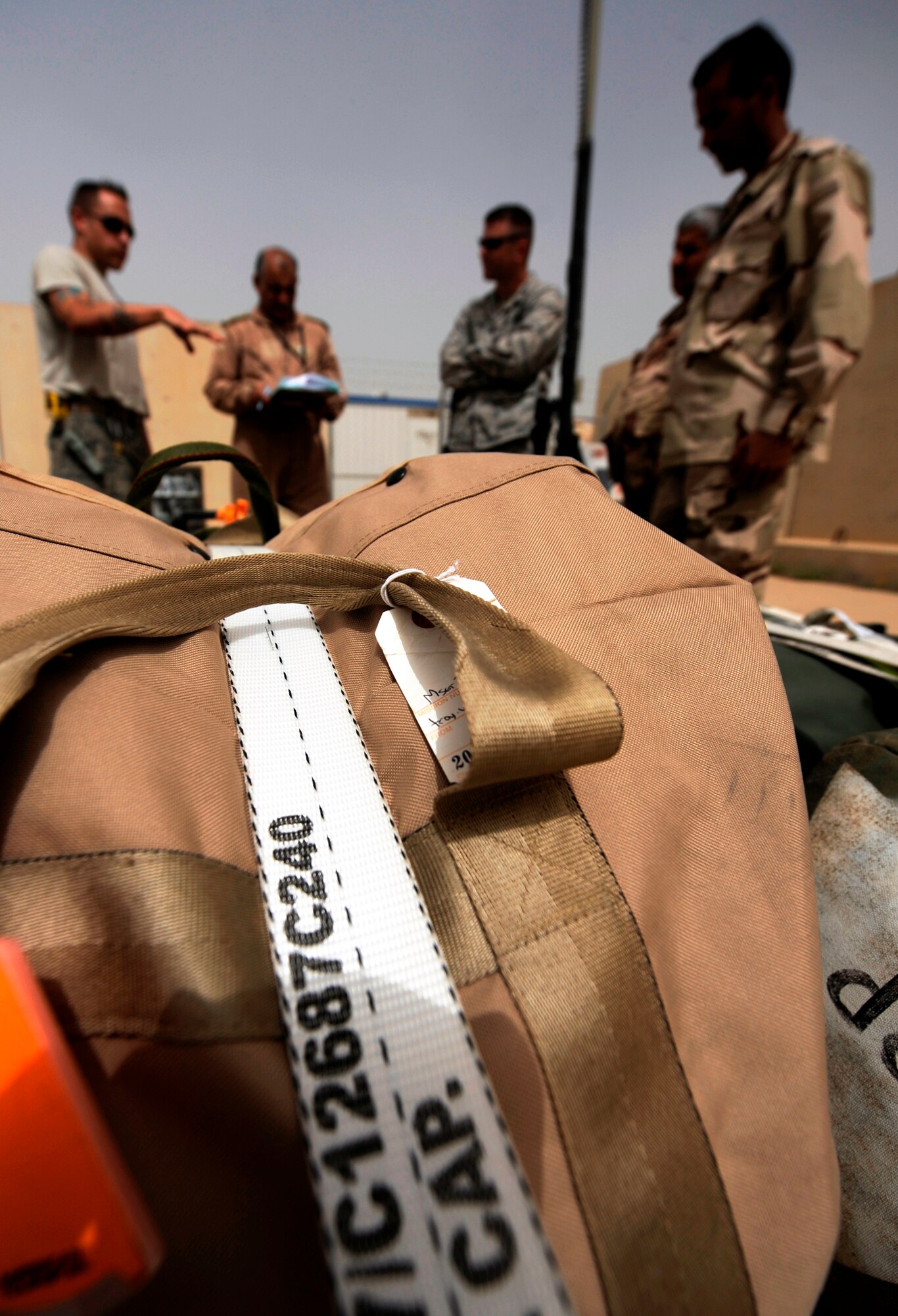 KIRKUK REGIONAL AIR BASE, Iraq -- Staff Sgt. Dane Childers, left, 321st Expeditionary Logistics Readiness Squadron, explains to his Iraqi partners the process of palletizing baggage and calculating baggage weight prior to loading it on board an aircraft. Sergeant Childers is a Guardsman deployed from the 166th Airlift Wing in New Castle, Del. (U.S. Air Force/Tech. Sgt. Jason Lake)