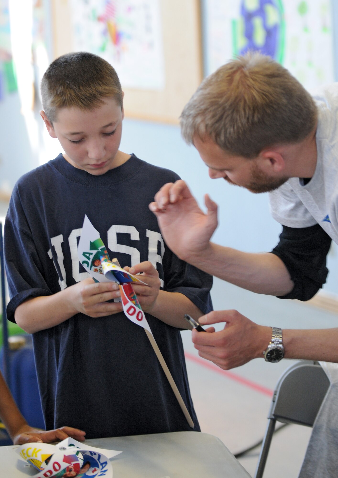 SPANGDAHLEM AIR BASE, Germany – Till Hellweg, right, helps Logan Gore, Spangdahlem Middle School sixth grade student, make a pinwheel during Spangdahlem Middle School’s Earth Day fair here April 21. Companies and organizations visited the school to teach students about the local environment, wildlife and how to conserve natural resources. (U.S. Air Force photo/Airman 1st Class Matthew B. Fredericks)