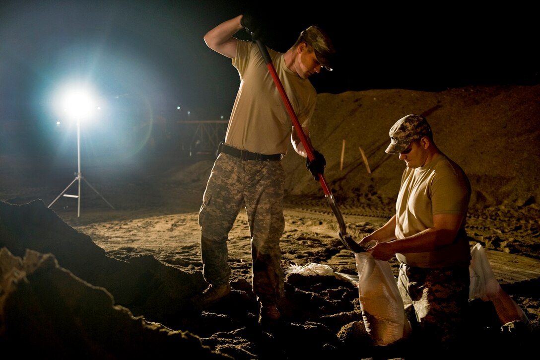 U.S. Army Spc. Benjamin Sukys and Spc. Robert Thorp work through the night filling sandbags at the Indiana Department of Transportation branch in Vincennes, Ind., April 26, 2011. Sukys and Thorp, both in the Indiana National Guard, are assigned to Company B, 1st Battalion, 151st Infantry Regiment.