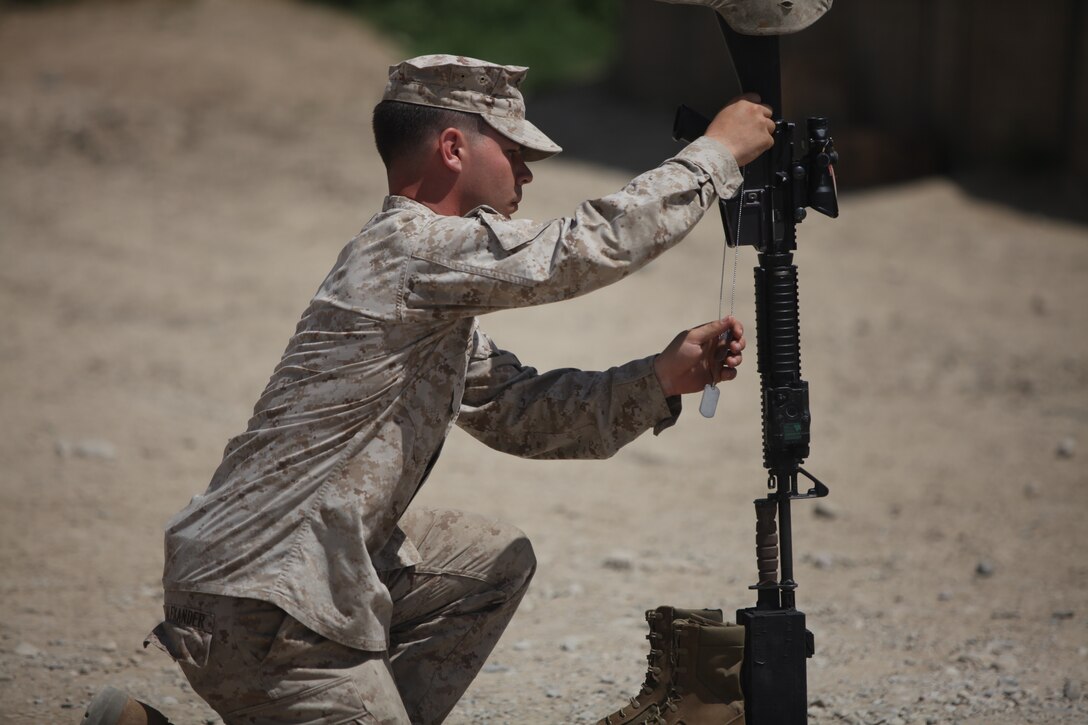 Sergeant Jarrod Alexander, a squad leader with 1st Squad, Company C, 2nd Combat Engineer Battalion, hangs dog tags off of a battlefield cross in memory of Staff Sgt. Jason Rogers, April 27.  The battlefield cross was dedicated in the memory of Rogers, who laid down his life trying to save two Marines in his command.