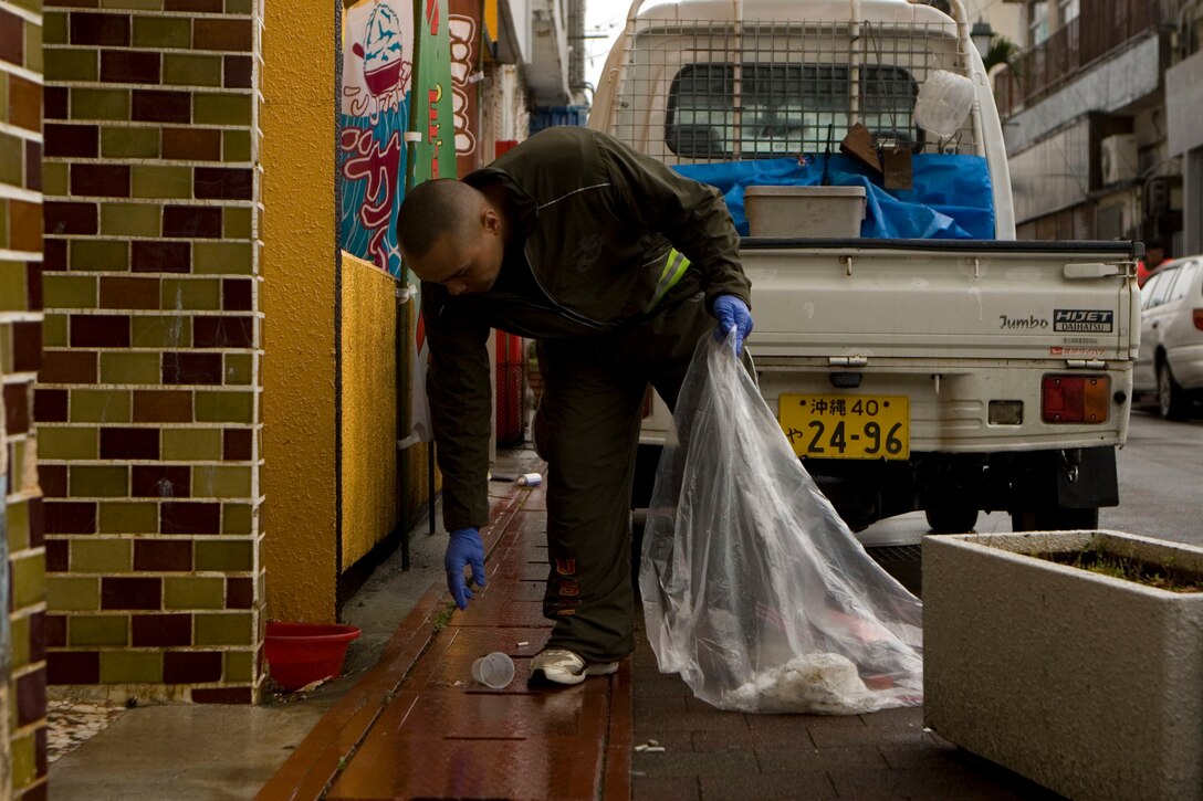 Lance Cpl. Freddy Ybarra, a team leader with Company G, Battalion Landing Team, 2nd Battalion, 5th Marines, 31st Marine Expeditionary Unit, picks up a plastic cup, April 27. Marines helped clean areas around the vicinity of Kin Town as part of a local community relations event.