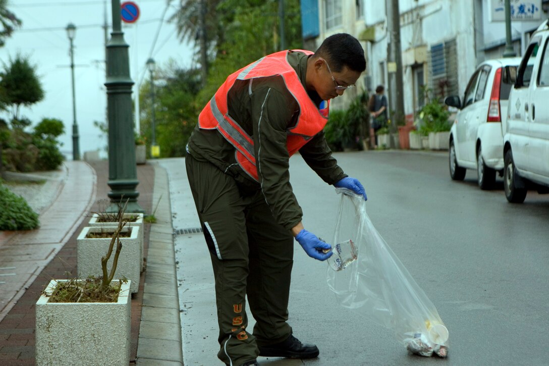 Lance Cpl .Aaron S. Kang, a combat engineer with Headquarters and Service Company, Battalion Landing Team 2nd Battalion, 5th Marines, 31st Marine Expeditionary Unit, picks up trash, April 27. Marines helped clean areas around the vicinity of Kin Town as part of a local community relations event.