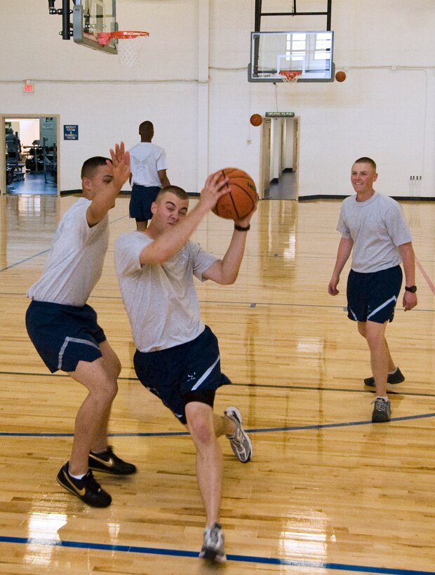 Airman 1st Class Eric Nieri, U.S. Air Force Honor Guard ceremonial guardsman, drives in for a layup against fellow honor guard members during a pickup game of basketball in the newly renovated basketball/volleyball court at the West Fitness Center April 27. (Photo by: Bobby Jones)