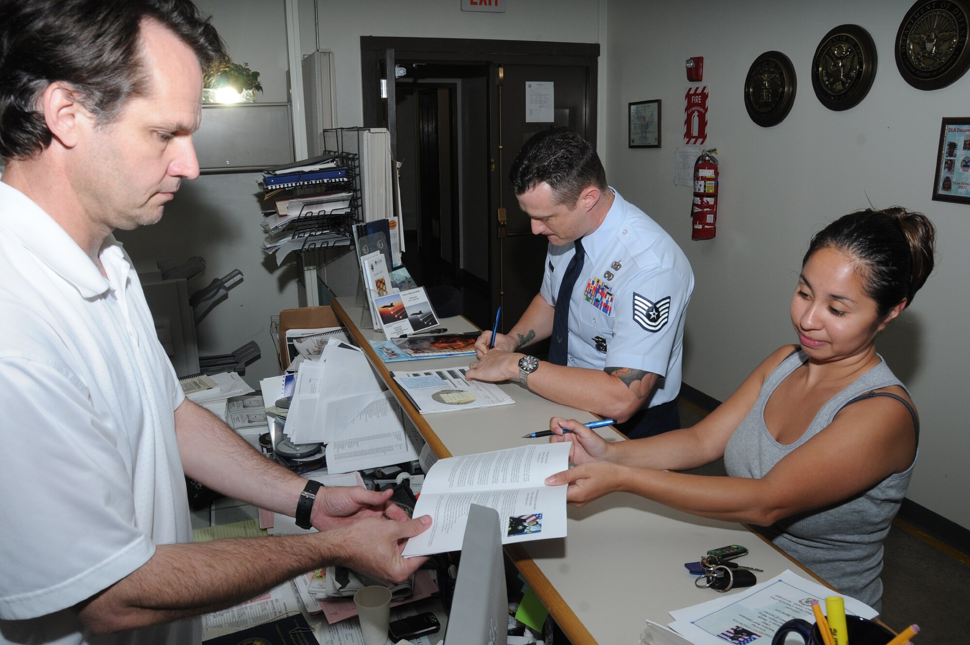 From left, electronic duplication specialist Barry Eubanks assists Tech. Sgt. Christopher Ré, 2nd Air Force, and Yeoman 2nd Class Rosann Hoffmann from Special Boat Team 22 at the Stennis Space Center with their printing needs.  (U.S. Air Force photo by Kemberly Groue)