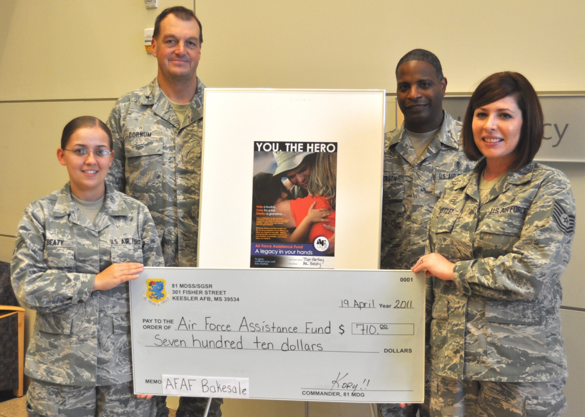 Airman 1st Class Ashley Beaty, left, and Tech. Sgt. Katherine Hartley, Air Force Assistance Fund representatives from the 81st Surgical Operations Squadron, hold a
check symbolizing the $710 they collected during an AFAF bake sale they organized and conducted in the hospital’s outpatient clinic lobby April 19. Brig. Gen. (Dr.)
Kory Cornum, 81st Medical Group commander, and Chief Master Sgt. Michael Anderson, 81st MDG superintendent, joined the pair in the lobby to congratulate
them for their initiative in raising funds for the worthwhile cause that benefits all Airmen and their families.  After raising $8,806 more last week, Keesler has raised
$42,281, nearly 52 percent of the base’s goal of $83,109 for this year’s campaign which runs through May 6.  (U.S. Air Force photo by Steve Pivnick)