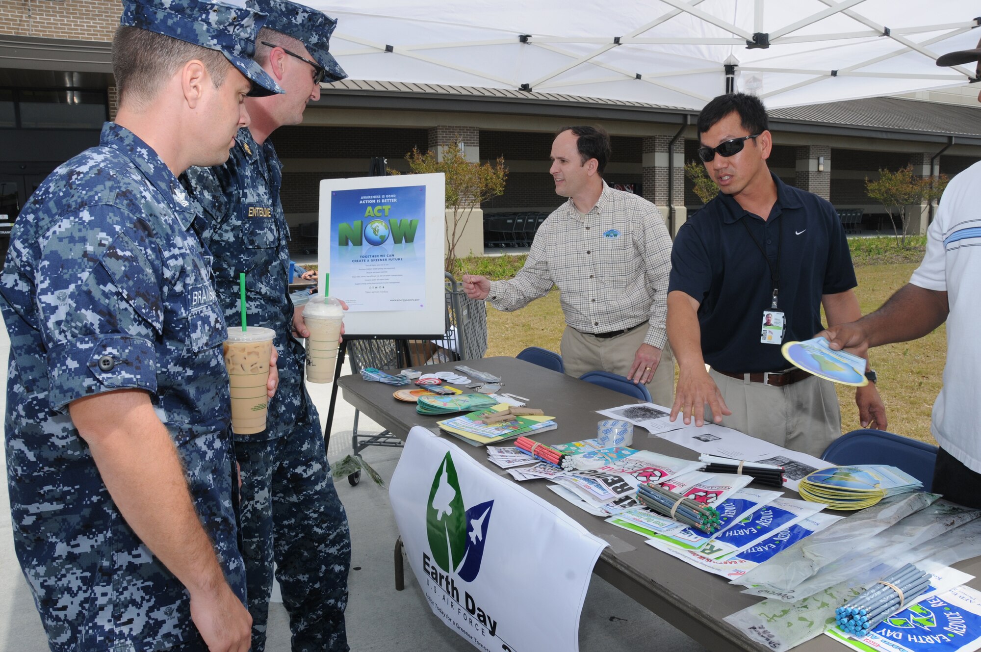 From left, Aerographer’s Mate 1st Class Joshua Branscum and Aerographer’s Mate Chief Jason Enterline from the Keesler Center for Naval Aviation Technical Training Unit receive energy literature and handouts from Adrian Barcomb, CSC resource efficiency manager, and Phi Dang, CSC environmental office, April 19 outside the base exchange. The energy conservation booth was part of the base’s Earth-Arbor Day observance.  (U.S. Air Force photo by Kemberly Groue)